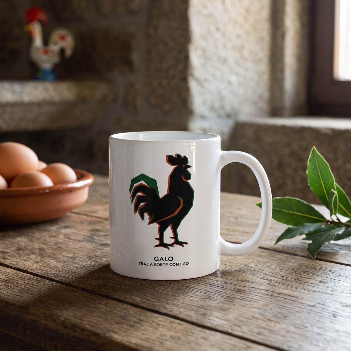 Mug Galo posé sur une table en bois dans une cuisine en pierre, bol d'œufs, feuilles vertes et coq de Barcelos peint sur l'étagère