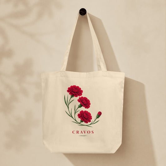 Sac tote crème oyster suspendu sur mur, bouquet d'œillets rouges et texte Cravos, série Œillets 25 avril Portugal TifoArt