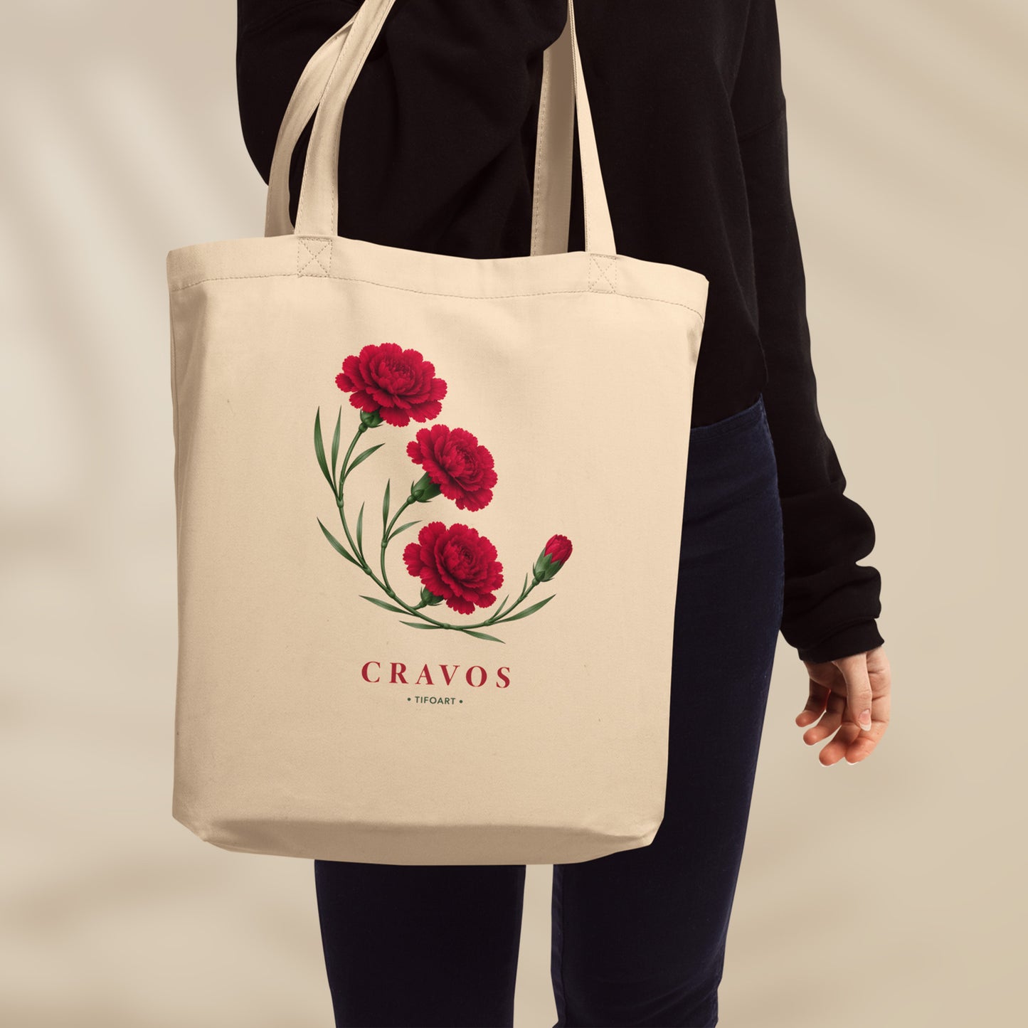 Sac tote crème porté à l'épaule, bouquet de trois œillets rouges et mot Cravos en serif rouge, série 25 avril Portugal TifoArt