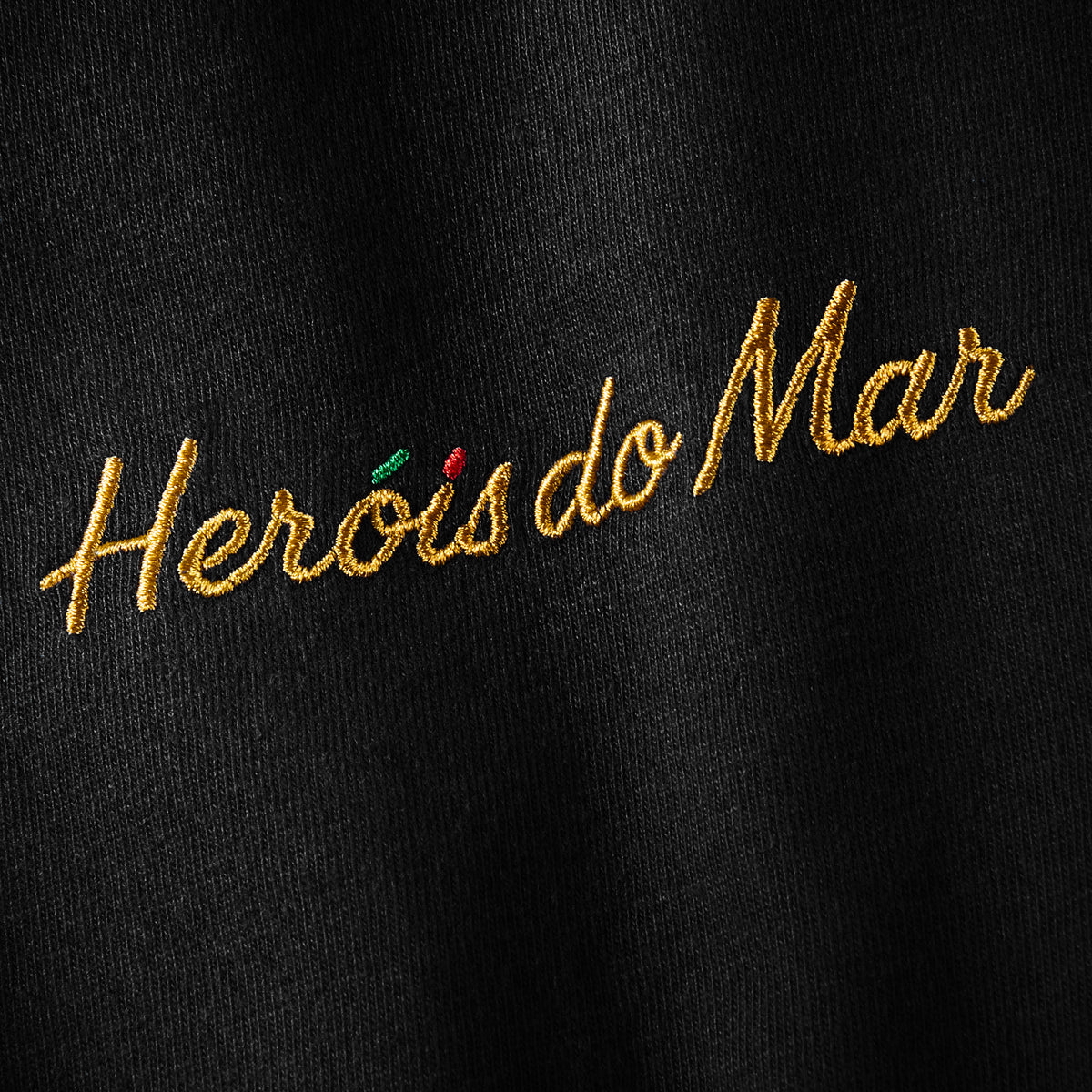 Gros plan serré de la broderie Heróis do Mar, fil doré sur coton Comfort Colors noir, t-shirt TifoArt