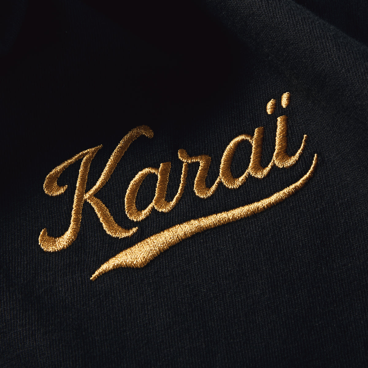 Gros plan de la broderie Karaï fil doré côté cœur sur coton Comfort Colors noir, t-shirt TifoArt