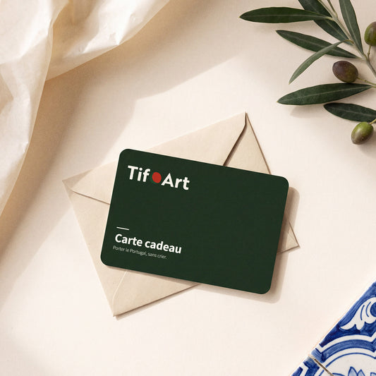 Carte cadeau TifoArt verte posée sur une enveloppe kraft, avec une branche d'olivier et un azulejo bleu et blanc