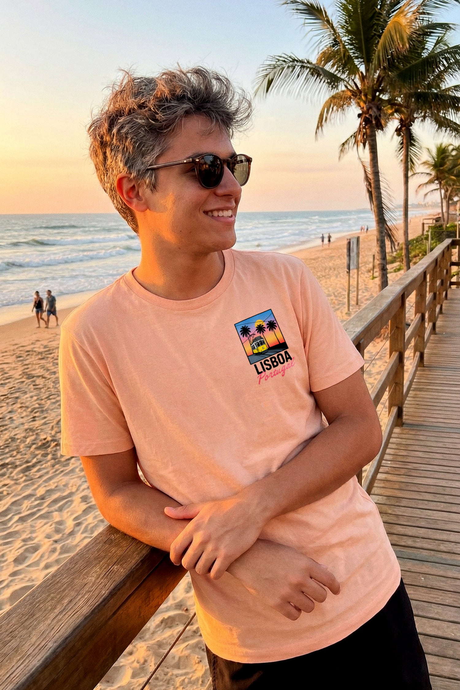 Jeune homme à lunettes de soleil sur un ponton de plage au coucher du soleil, vêtu du t-shirt Lisboa Portugal de TifoArt