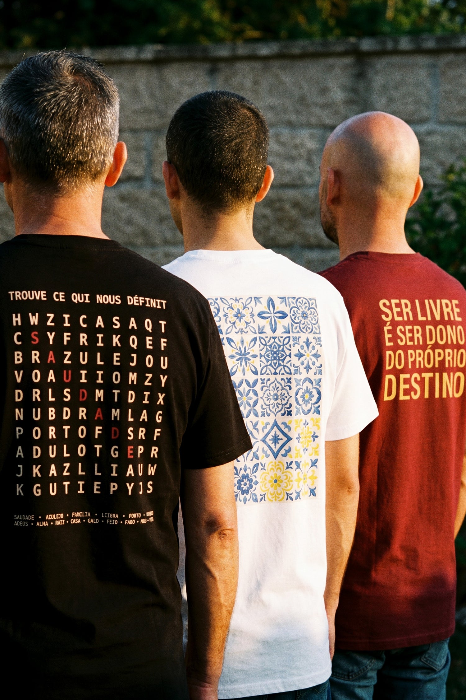 Les trois frères fondateurs de TifoArt de dos, vêtus de t-shirts aux motifs portugais, sous la lumière dorée du soir